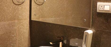 Un baño con un lavabo redondo, un espejo y un perchero para toallas.