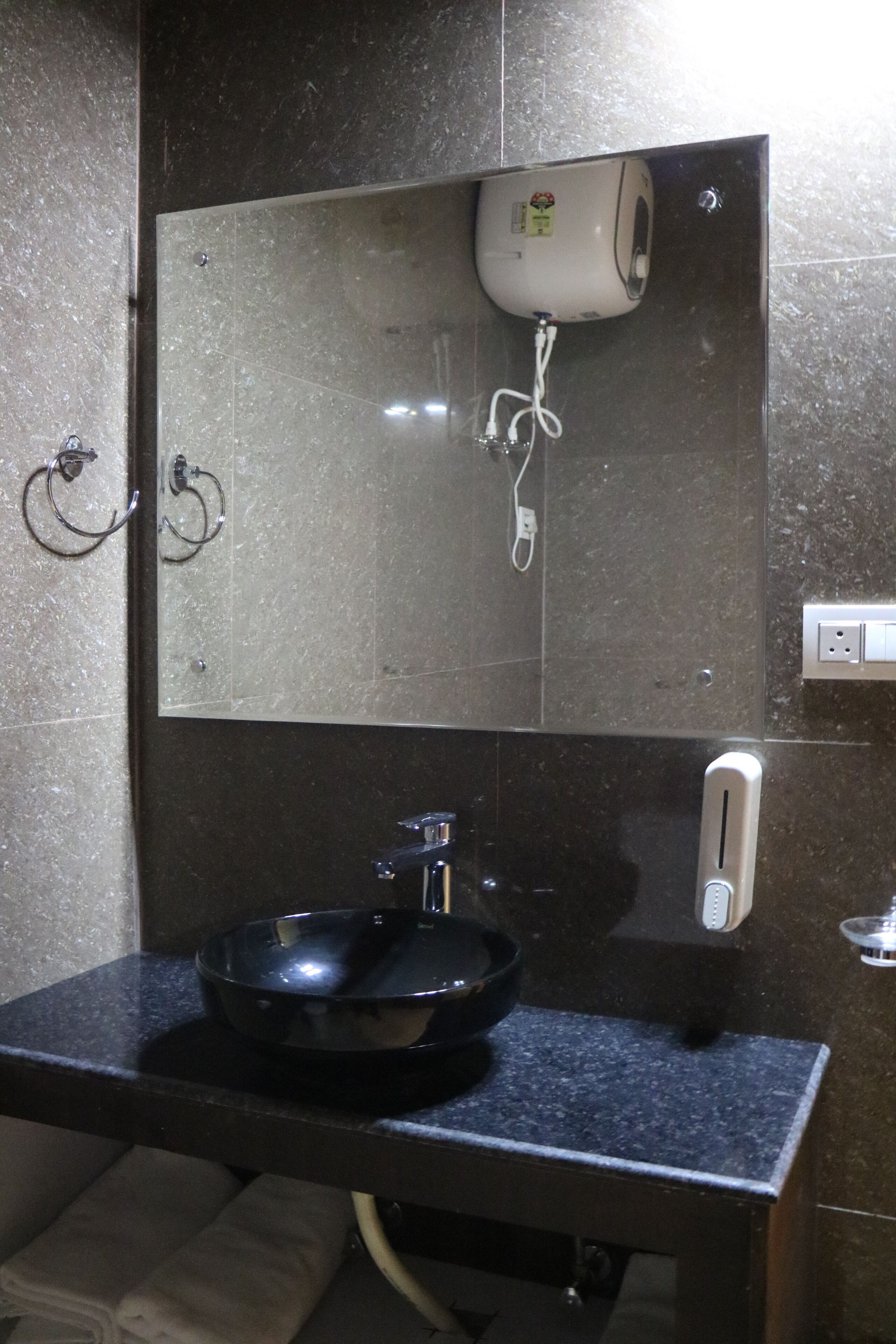 A bathroom with a black sink, a mirror, a hairdryer, and a towel rack.