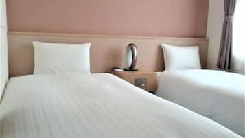 Quarto de hotel com duas camas, uma mesa de cabeceira com espelho e uma parede lisa.