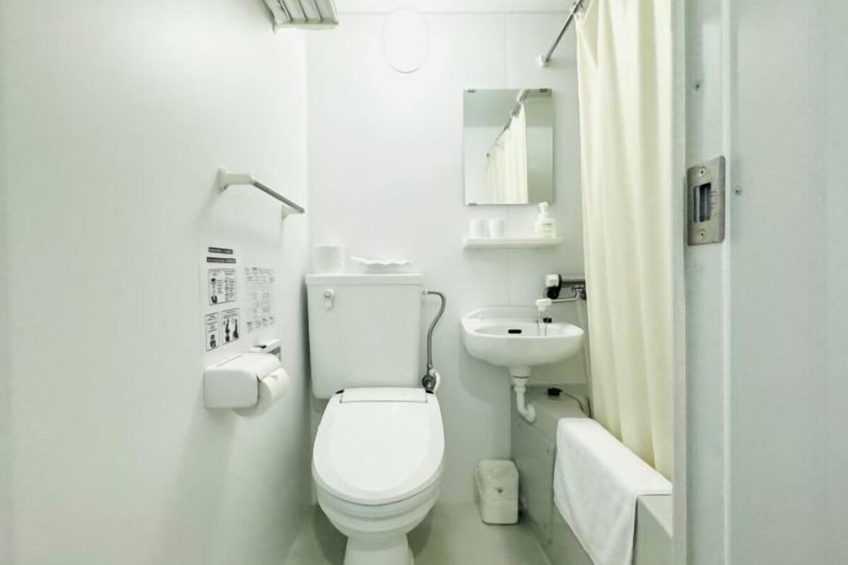 Un baño pequeño y blanco con inodoro, lavamanos y espejo.