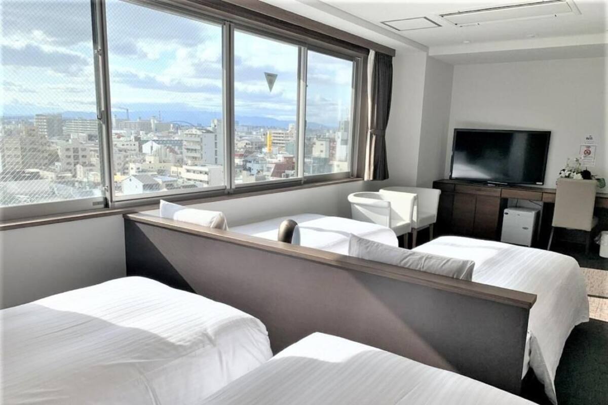 Une chambre d’hôtel avec deux lits, une télévision et une vue sur la ville.