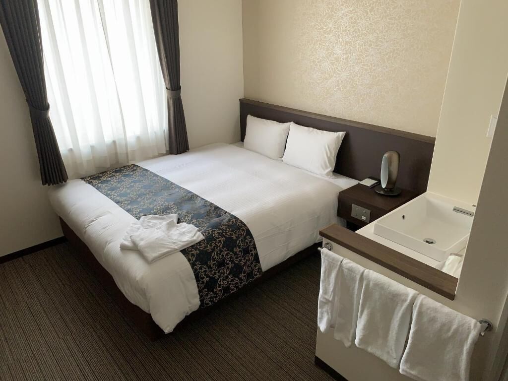 Ein Hotelzimmer mit Bett, Nachttisch, Spiegel und einem Badebereich.