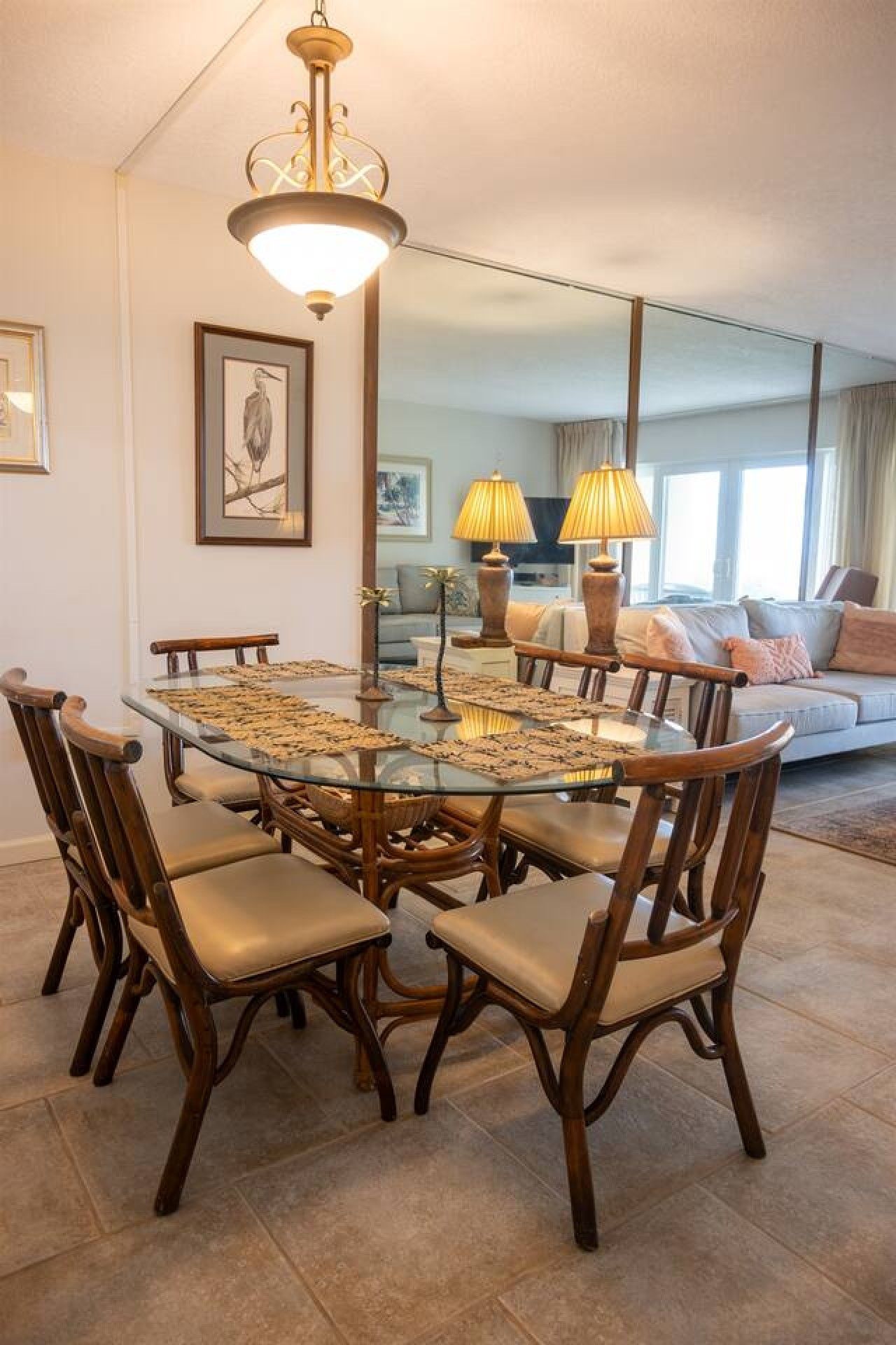 Un espace repas avec une table à plateau de verre, entourée de chaises en bois dotées d’assises rembourrées.