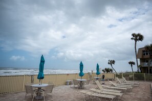 Eine Strandterrasse mit Liegestühlen, Tischen und Sonnenschirmen mit Blick auf den Ozean.