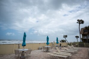Eine Terrasse direkt am Strand mit Liegestühlen und Tischen mit Blick auf das Meer.