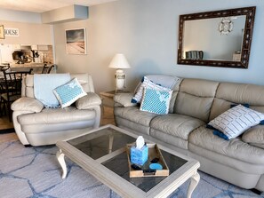 A living room with a sofa, armchair, coffee table, and a dining area in the background. - Ground-Floor Oceanfront Condo | Steps to Beach (Saint Augustine)