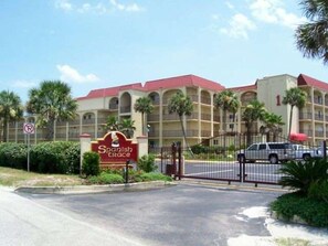 Ein Hotel in Spanien mit einem begrenzten Eingangsbereich, Palmen und einem Gebäude mit rotem Dach.