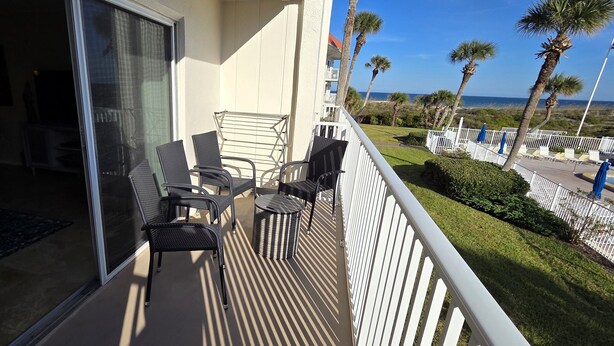A balcony with outdoor furniture, a view of the ocean, and a well-maintained lawn. - Oceanview Townhouse with Pool & Balcony Access (Saint Augustine)