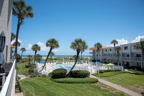 A resort with a pool, palm trees, and a view of the beach.