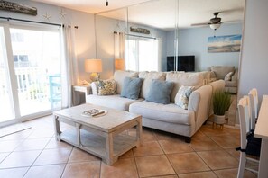 Un salon avec un canapé, une table basse, un téléviseur et un balcon.