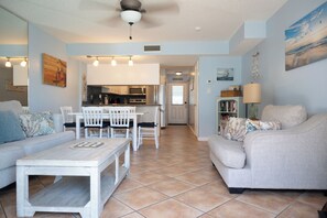 A living room with a sofa, a coffee table, and a dining area with chairs and a table.