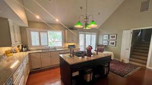 A spacious kitchen with a large island, built-in appliances, and a view of the outdoors through the windows. - The Pearl by Sandpiper | Near Beach (Seabrook Island)