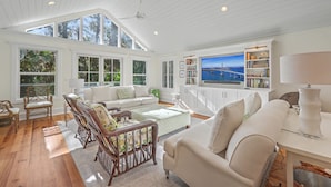 A spacious living area with a high ceiling, large windows, and a view of a bridge. - Mystic Pines by Sandpiper | Near Beach (Seabrook Island)