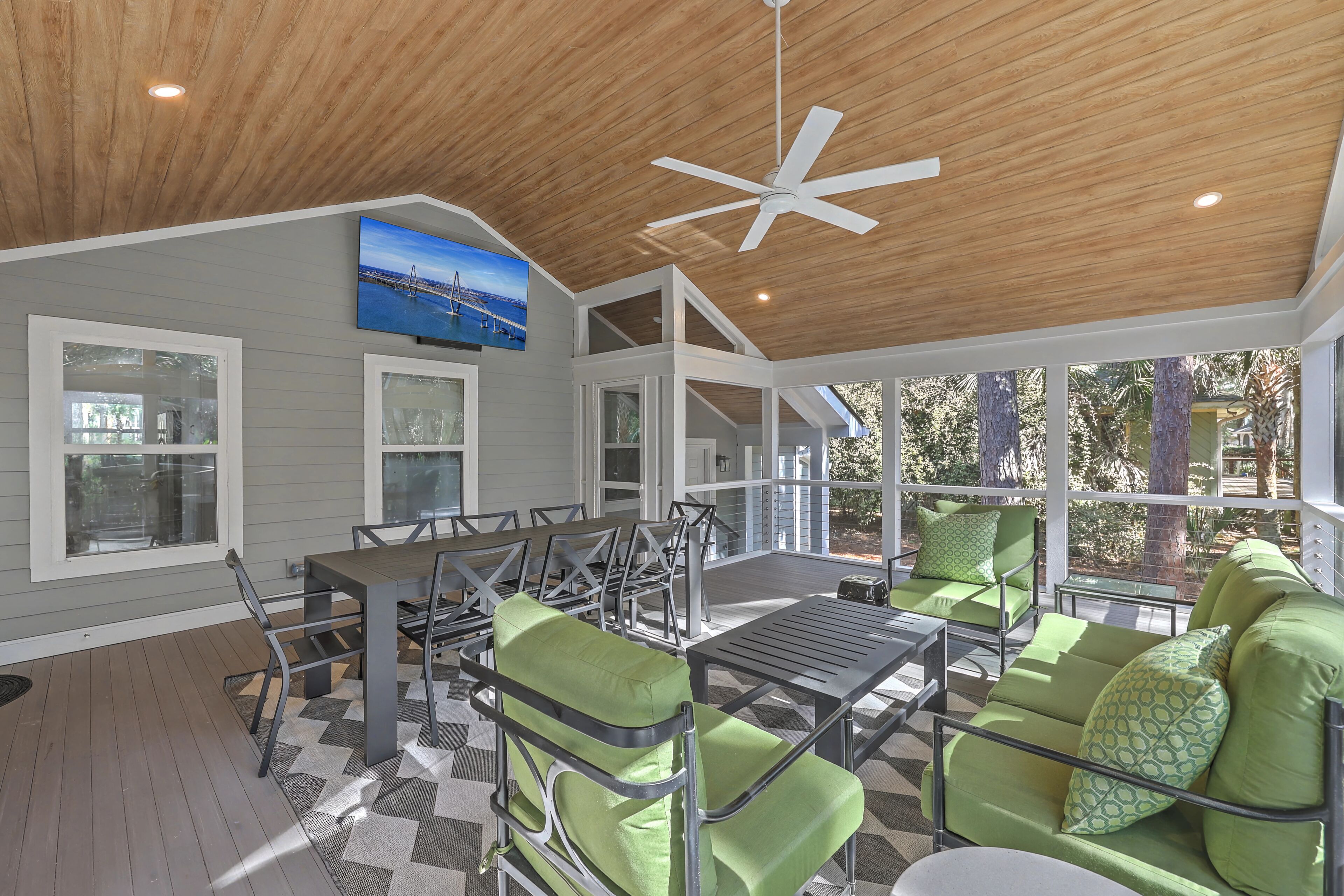 A covered patio with a ceiling fan, a dining table with chairs, and a sofa with cushions.