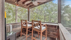 A covered outdoor seating area with wooden chairs and a ceiling fan. - Escape to The Hummingbird Treehouse, a luxury retreat. Pet friendly (Wadmalaw Island)