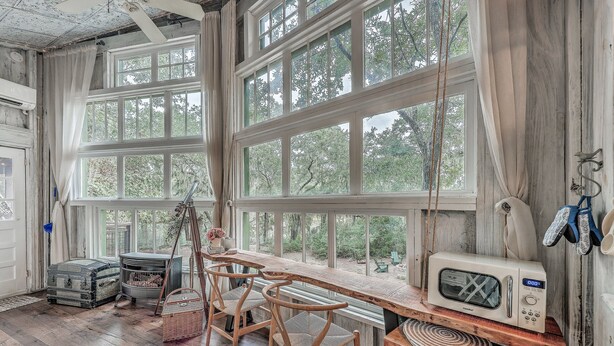 A rustic kitchen with wooden furniture, large windows, and a microwave. - Escape to The Hummingbird Treehouse, a luxury retreat. Pet friendly (Wadmalaw Island)