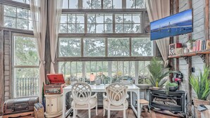 Una habitación acogedora con un amplio ventanal, suelo de madera, televisor, radio antigua y chimenea.