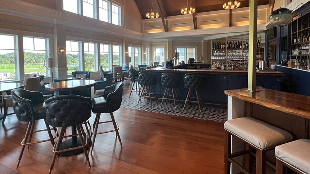 A spacious bar area with high ceilings, large windows, and a view of the outdoors. - Ocean Winds Escape by Sandpiper | Near Beach (Seabrook Island)