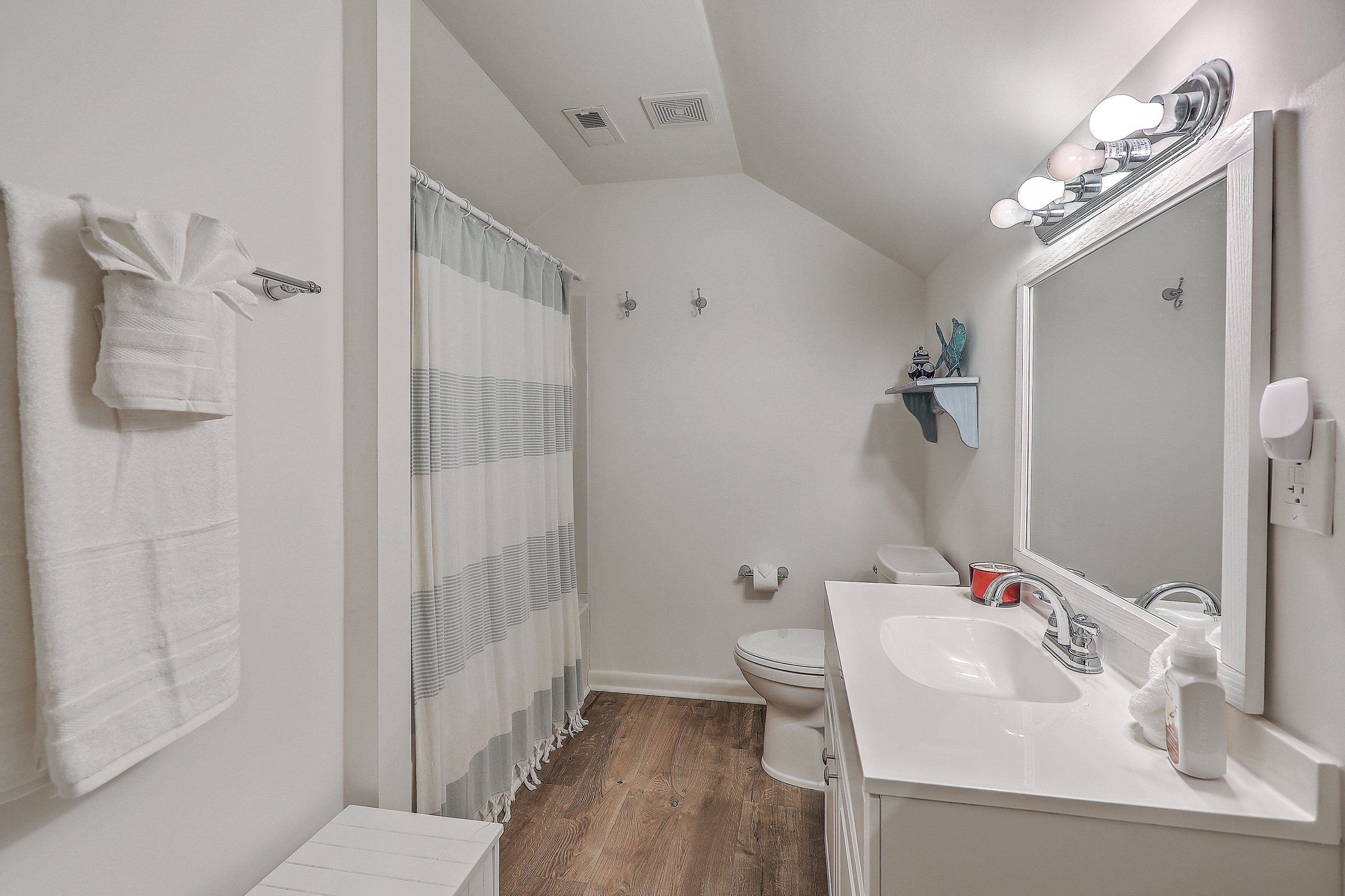 Een badkamer met douche, toilet, wastafel en een spiegel met verlichting.