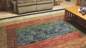 Une pièce chaleureuse avec un mur en bois, un canapé, une petite table et un tapis coloré.