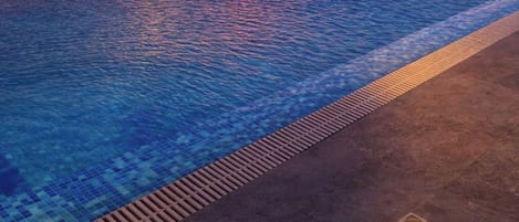 A pool with a view of the sunset over the water.