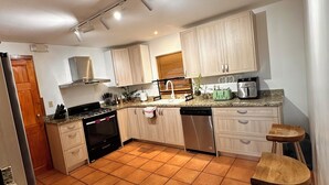Une cuisine moderne avec des meubles en bois clair, une cuisinière en acier inoxydable et un lave-vaisselle.