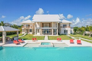 Una casa grande de dos pisos con piscina delantera.