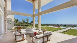 A spacious outdoor seating area with a pool and ocean view. - Okyanus: Spectacular oceanview estate w/ pool, Jacuzzi, full staff & golf cart (Punta Cana)