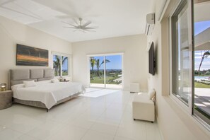 A spacious bedroom with a large bed, a ceiling fan, and a view of the outdoors.