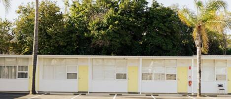 A row of single-story motel rooms with a parking lot in front.