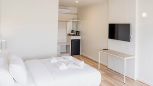 A modern hotel room with a large bed, a TV mounted on the wall, a desk, and a wardrobe. - Sunnyside Motel (Port Broughton)