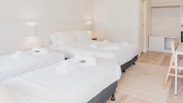 A hotel room with two beds, a desk, and a wardrobe. - Sunnyside Motel (Port Broughton)