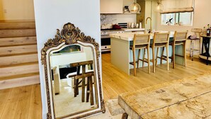 Una cocina moderna con una isla central, taburetes de bar y un espejo grande.