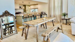 Una sala moderna con una mesa de comedor de madera, bancos y un espejo grande.