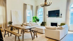 Amplia sala de estar con una mesa de comedor de madera, un sofá y un televisor montado en la pared.