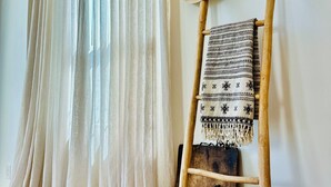 Una habitación con una escalera de madera, una manta tejida y un sombrero de paja.