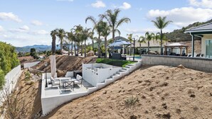 Un patio exterior moderno con piscina, mobiliario y una pérgola.