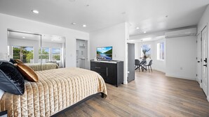 Un dormitorio moderno con una cama grande, un televisor y un comedor con una mesa y sillas.