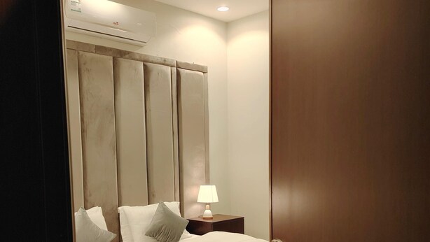 Un dormitorio con cama, lámpara de noche y una puerta de madera.
