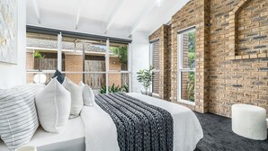 Une chambre moderne avec un grand lit, un mur en briques et une vue sur l’extérieur.