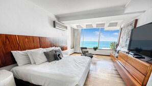 A modern hotel room with a large bed, a TV, and a view of the ocean. - Beachfront Oasis with a View - Puerto Vallarta (Puerto Vallarta)