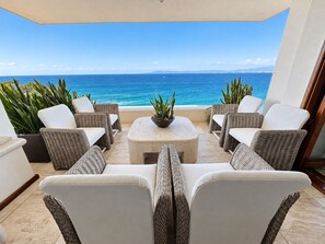 Una terraza con mobiliario de mimbre, una mesa central y plantas en macetas.