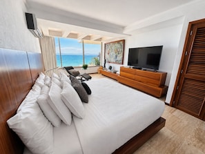 Une chambre moderne avec un grand lit, une télévision et une vue sur la mer.