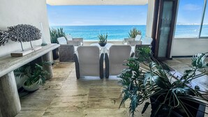 A room with a view of the ocean, wicker furniture, and potted plants. - Beachfront Oasis with a View - Puerto Vallarta (Puerto Vallarta)