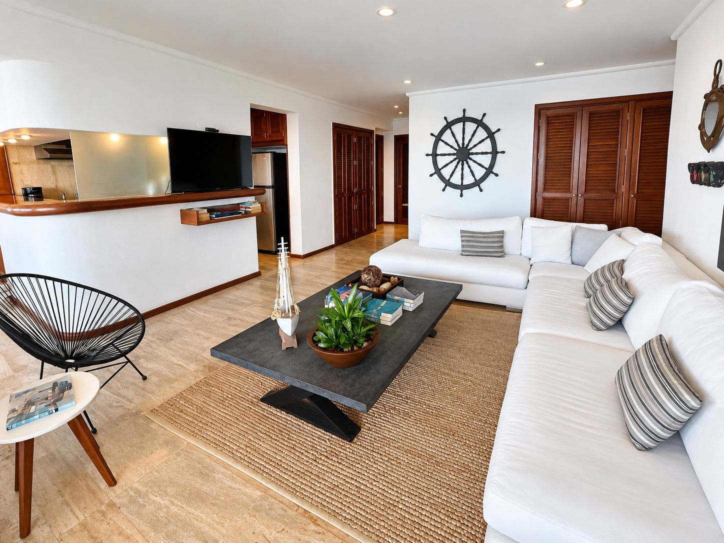 A modern living room with a sofa, a coffee table with decorative items, a television, and a wooden cabinet.
