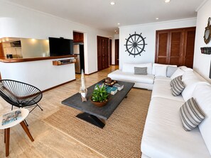 Una sala moderna con un sofá, una mesa de centro con objetos decorativos, un televisor y un mueble de madera.