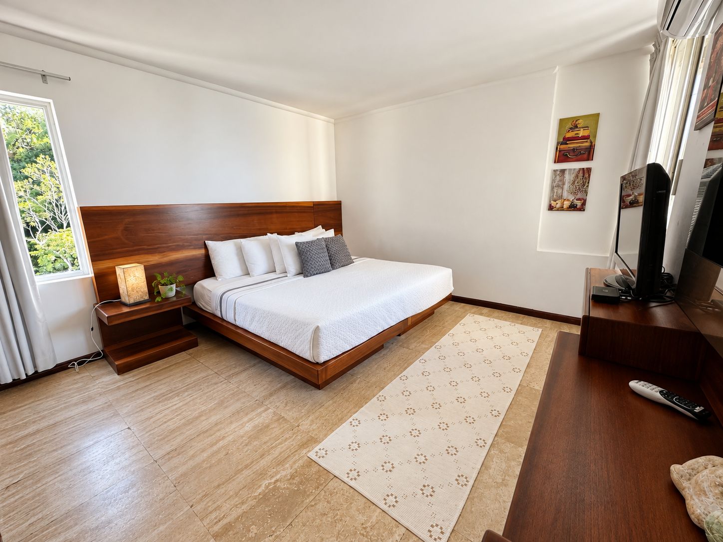 A modern bedroom with a wooden bed, bedside tables, a TV, and a window with curtains.