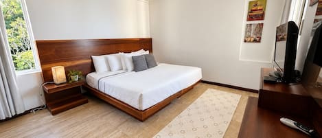 A modern bedroom with a wooden bed, bedside tables, a TV, and a window with curtains.
