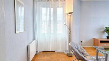 Una sala de estar moderna con un radiador, una lámpara de pie, una silla plegable y una mesa de vidrio.