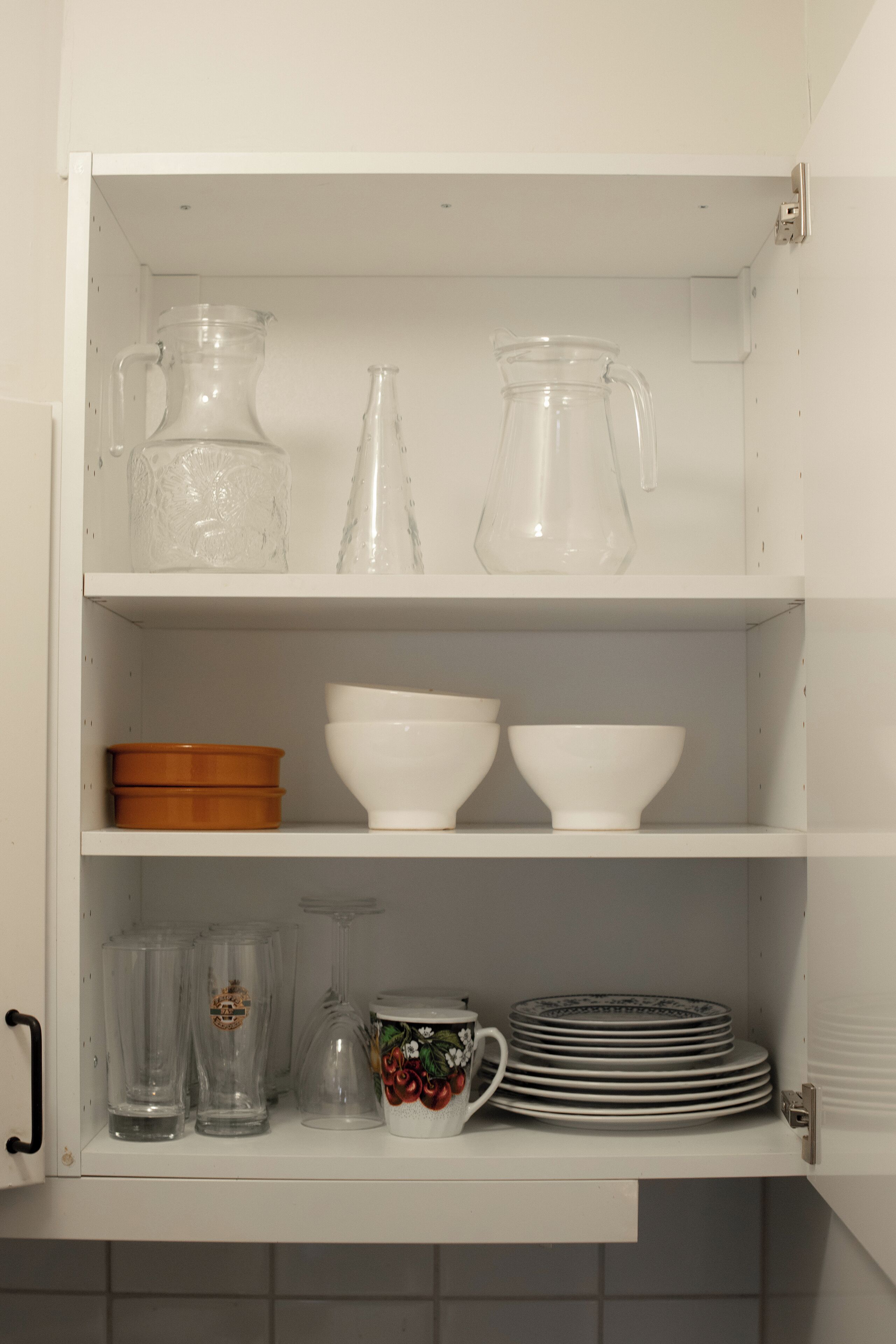 Un meuble de cuisine contenant de la verrerie, des bols et des assiettes.